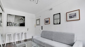 A modern living room with a grey sofa, white stools, and a glass coffee table. - Paris Marais Best Trip (Paris)