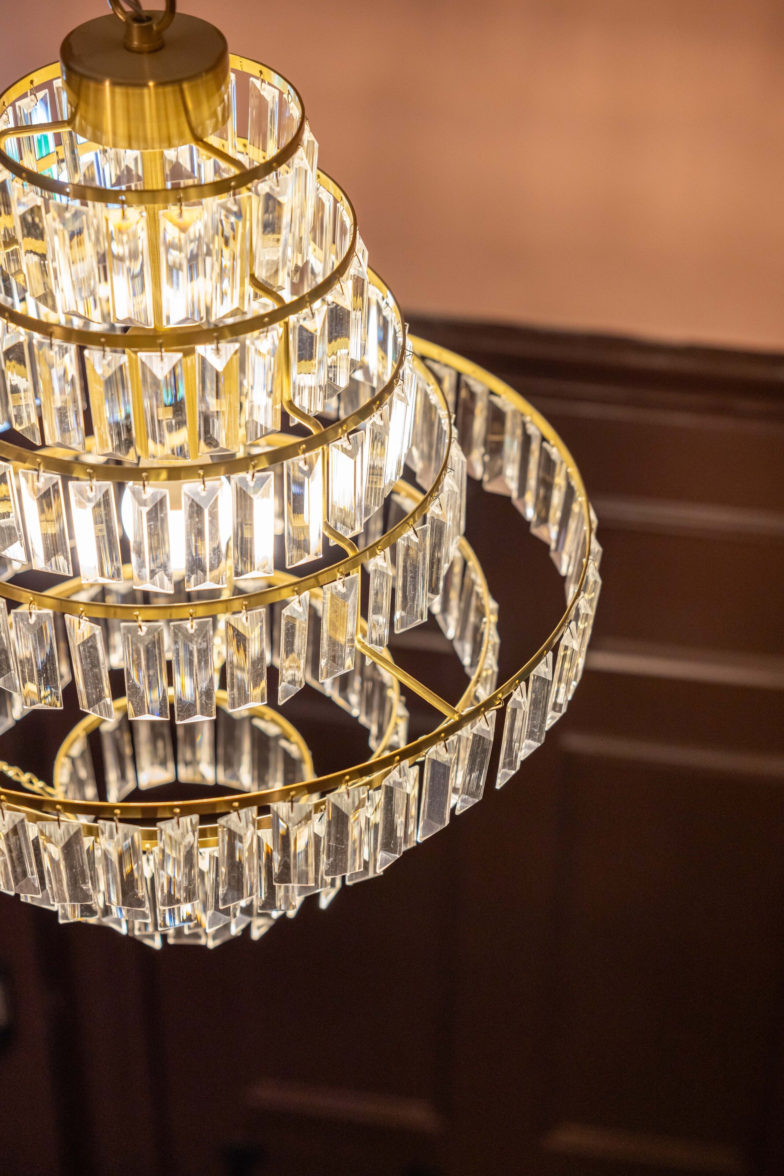 A chandelier with multiple tiers of clear crystal prisms and a gold-colored frame.
