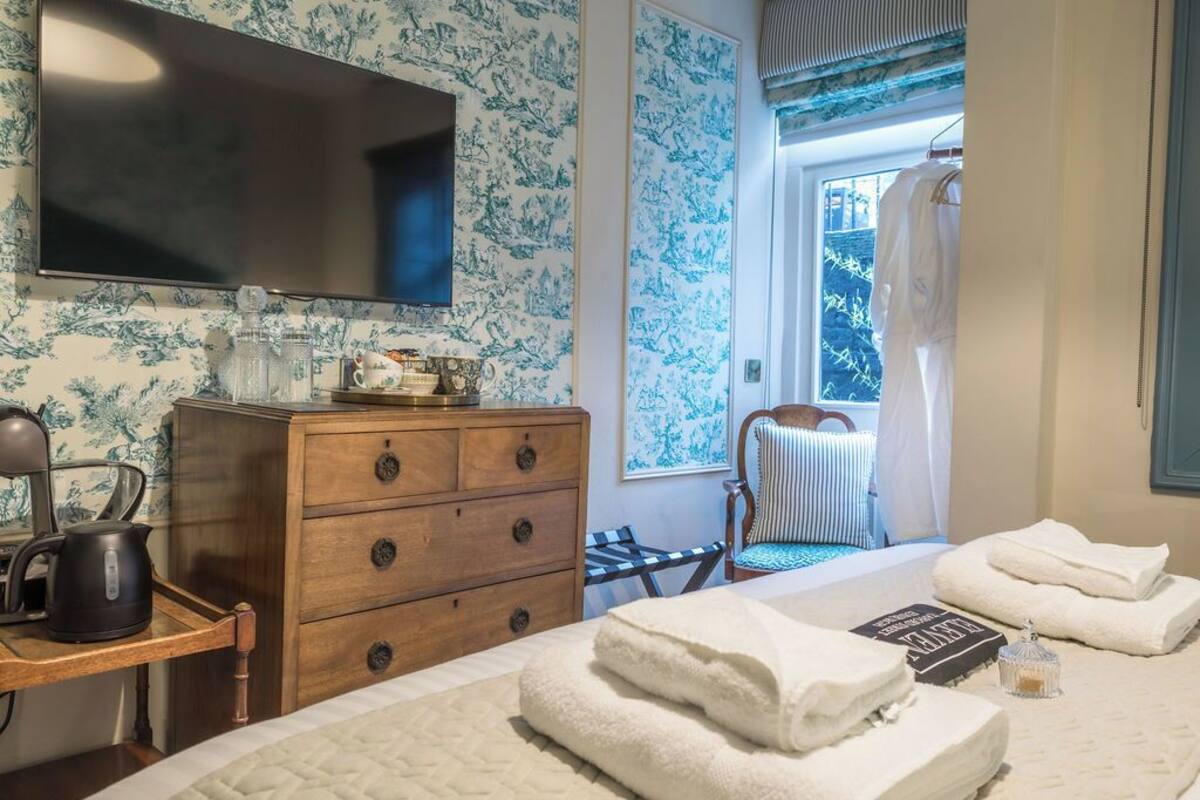 Een hotelkamer met een bed, een houten dressoir, een televisie en een raam met uitzicht op bomen.