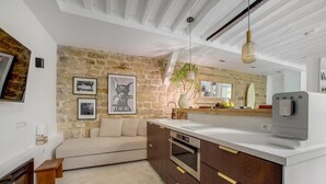 A modern kitchen with a stone wall, a sofa, a coffee machine, and a hanging light fixture. - Hot Hot Hot Loft Faubourg Saint-Denis (Paris)