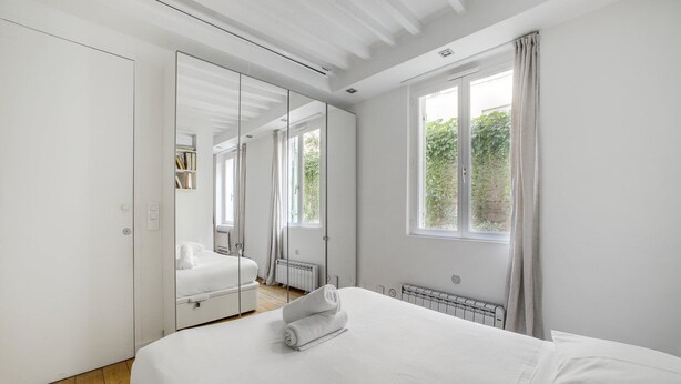 A bedroom with a large bed, a wardrobe, a mirror, and a window with curtains. - Hot Hot Hot Loft Faubourg Saint-Denis (Paris)