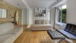 A modern living room with a stone wall, a sofa, a coffee table, and a black leather bench. - Hot Hot Hot Loft Faubourg Saint-Denis (Paris)