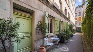 A narrow alley with a green door, a small table with chairs, and potted plants. - Hot Hot Hot Loft Faubourg Saint-Denis (Paris)