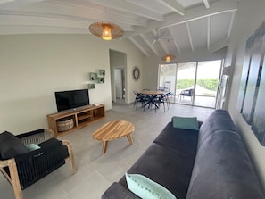 Uma sala de estar moderna com televisão de tela plana, mesa de centro de madeira e um sofá escuro.
