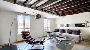 Un salon moderne avec un fauteuil en cuir, une table basse en verre et un canapé.