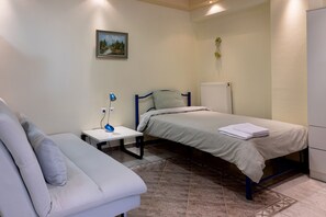 A bedroom with a bed, a bedside table, a lamp, a radiator, and a small plant. - Zant House Trikala Town (Trikala)
