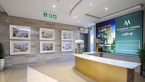 A reception area with framed pictures on the wall, a reception desk, and a sign for Masingita Towers luxury apartments. - Sandton Smart Apartment Seventeen (Sandton)