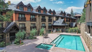 A hotel with a pool area, stone walls, and multiple balconies. - Walk to Chair 6 + Mountain Views | Chalet Crevasse (Vail)