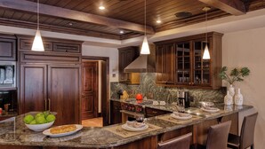 A kitchen with dark wood cabinets, a granite countertop, and pendant lighting. - Walk to Chair 6 + Mountain Views | Chalet Crevasse (Vail)