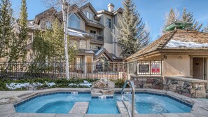 A two-story building with a swimming pool, stone walls, and a metal fence. - Walk to Arrow Bahn Express | Icegrass Chalet (Edwards)