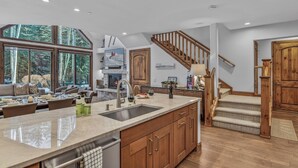 A spacious kitchen with a large island, wooden cabinets, and a view of the outdoors. - Walk to Arrow Bahn Express | Icegrass Chalet (Edwards)