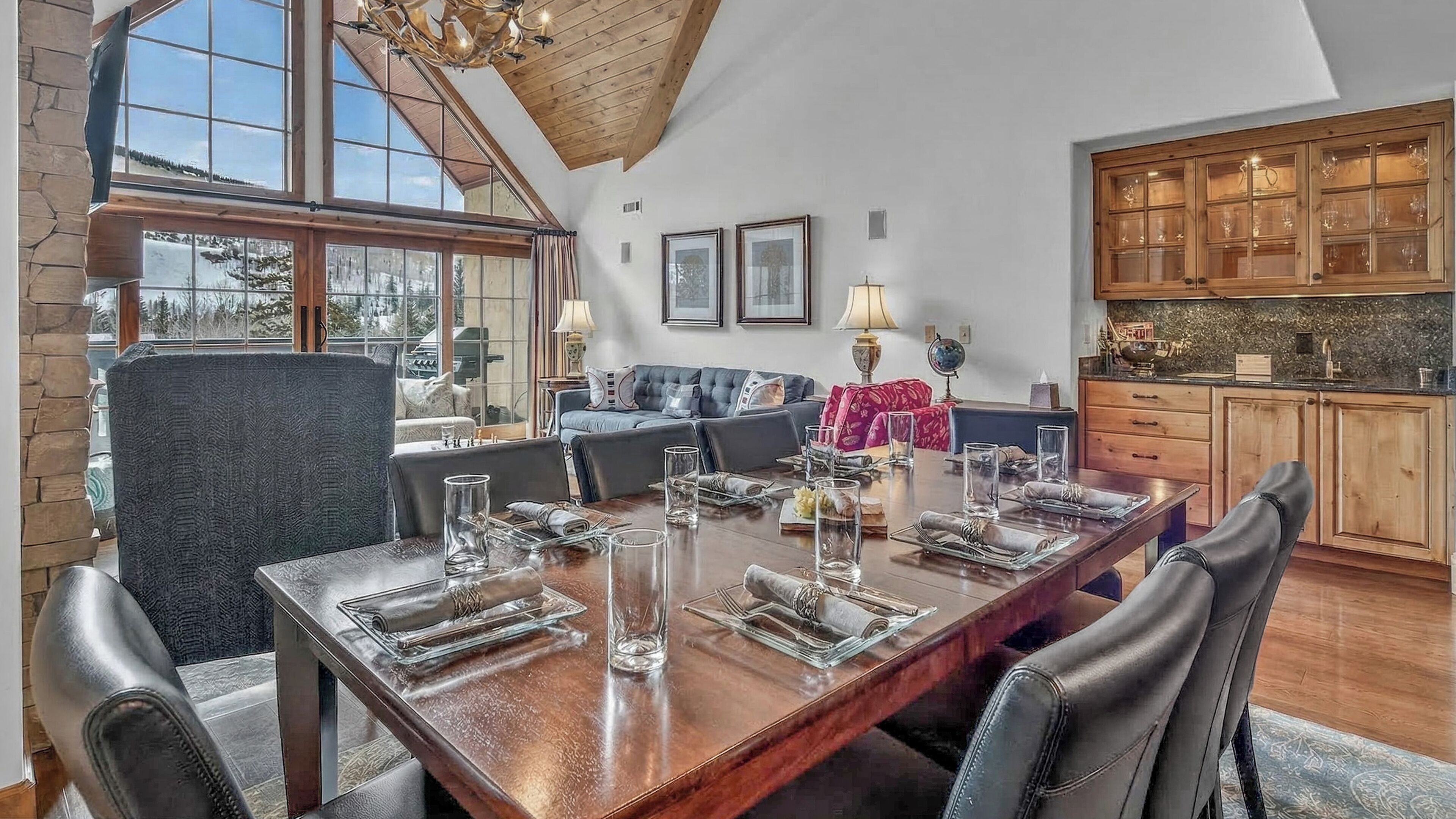 Een eetgedeelte met een grote houten tafel voor vier personen, een bank en een keuken met houten kasten.