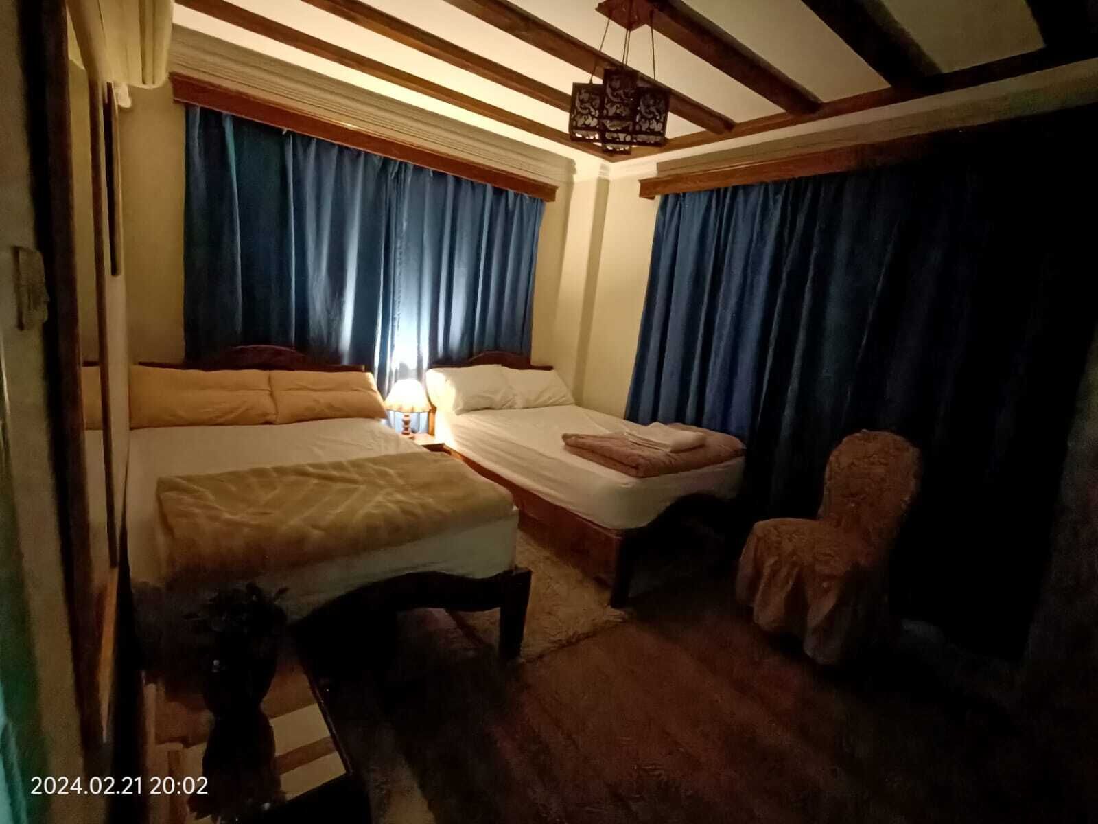 Ein Zimmer mit zwei Betten, einem Sessel und einer Pendelleuchte.