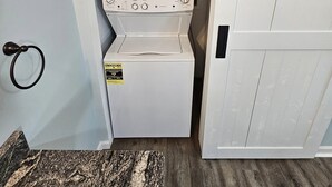 A compact laundry room with a washer and dryer, a wooden floor, and a small rug.
