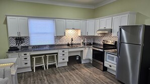 A modern kitchen with white cabinets, a stainless steel refrigerator, and a herringbone patterned backsplash.