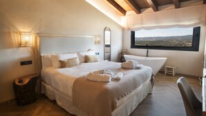 Une chambre avec un grand lit, une baignoire et une vue sur le paysage.