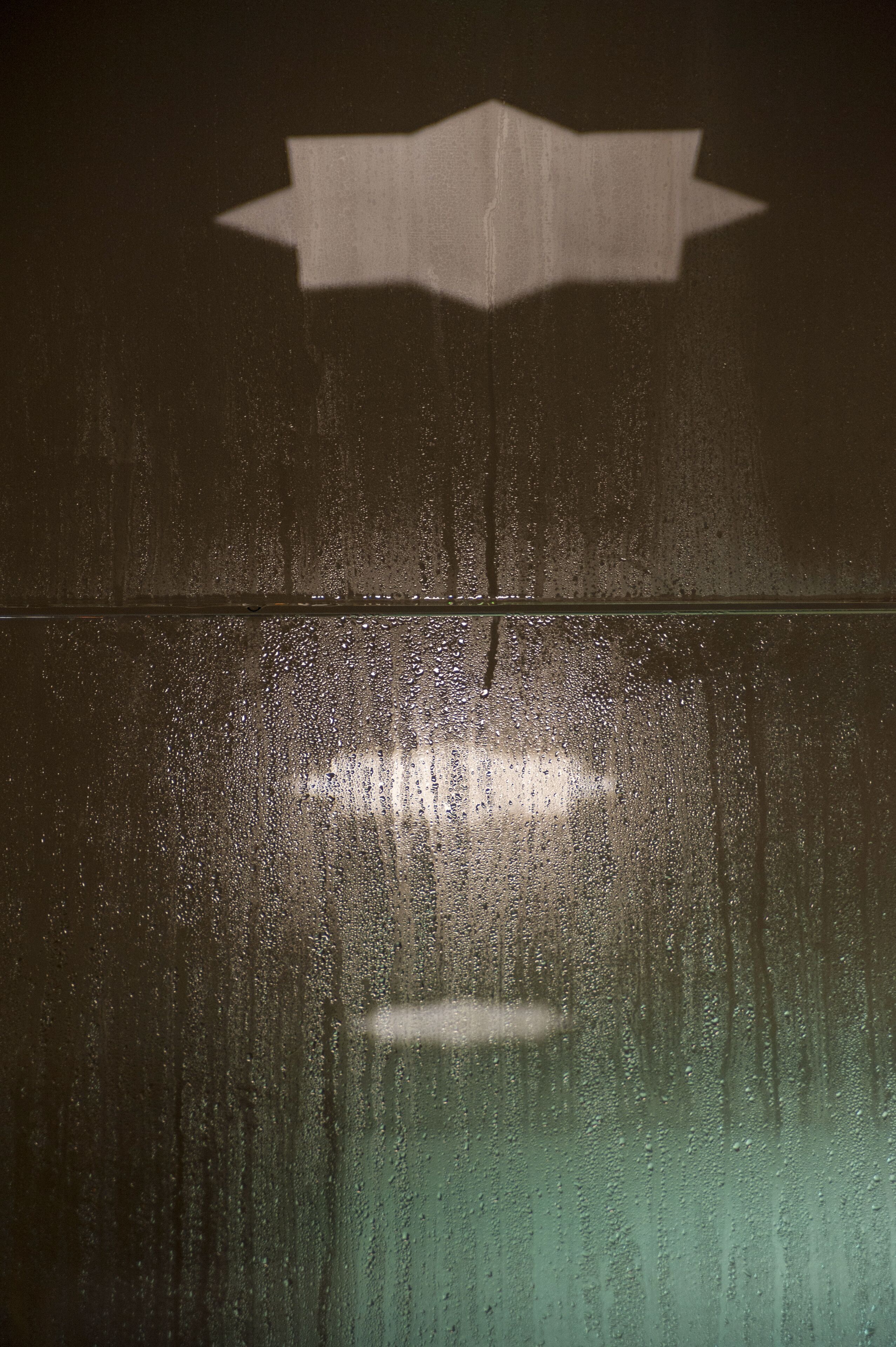 A glass surface with water droplets and a white arrow pointing to the right.
