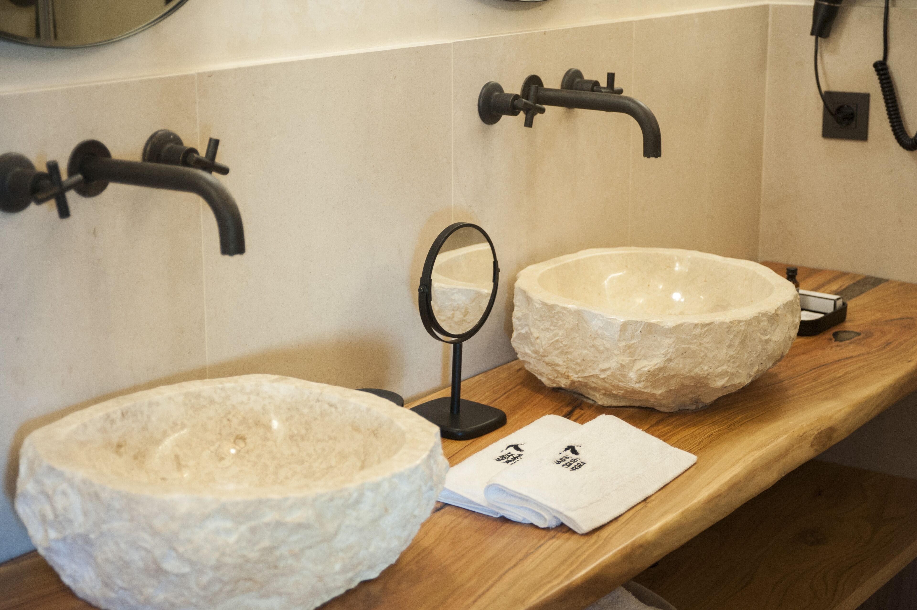 A bathroom with a stone sink, a mirror, and a towel rack.