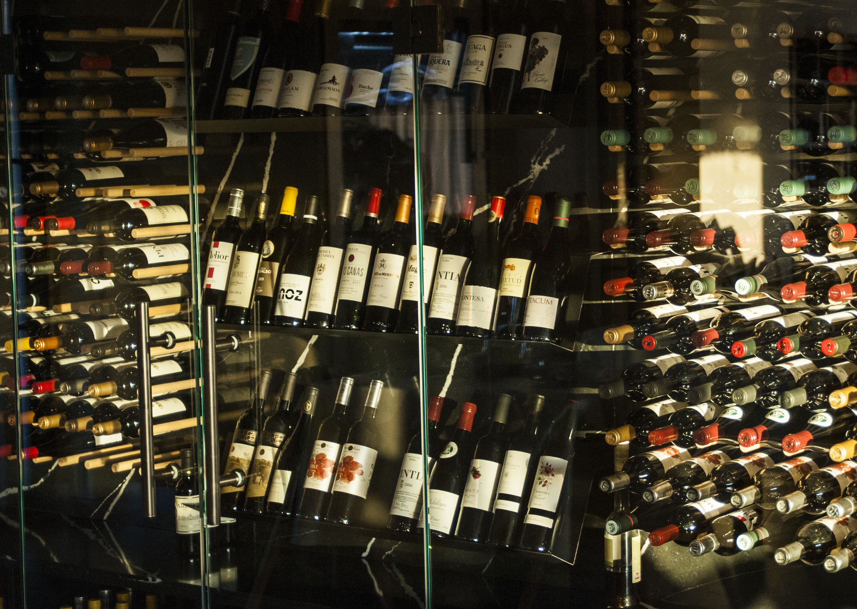 A wine cellar with numerous bottles of wine organized on shelves.