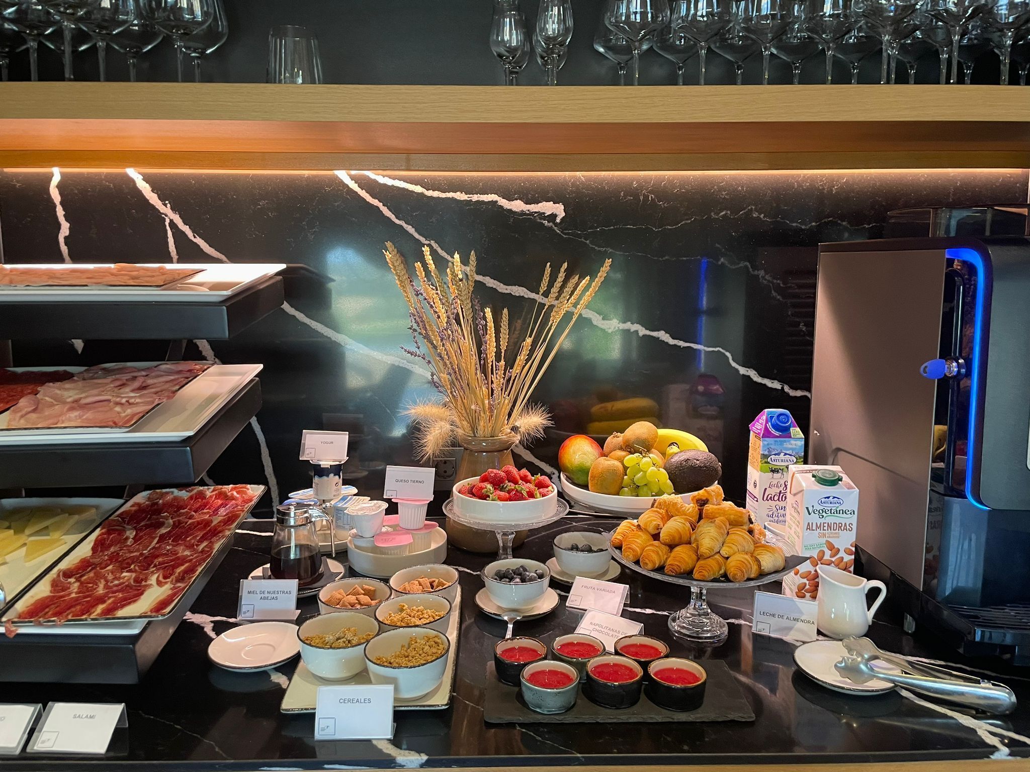Un bufé con diversos alimentos, incluyendo carnes, quesos, frutas y pastelería.