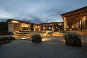 Un hotel con fachada de piedra, zona de estar al aire libre y una escalera que conduce a la entrada.