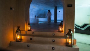 Une entrée en arc, par laquelle passe une personne, mène à un espace faiblement éclairé, décoré de lanternes et sur lequel on peut lire l’inscription « Hammam ».