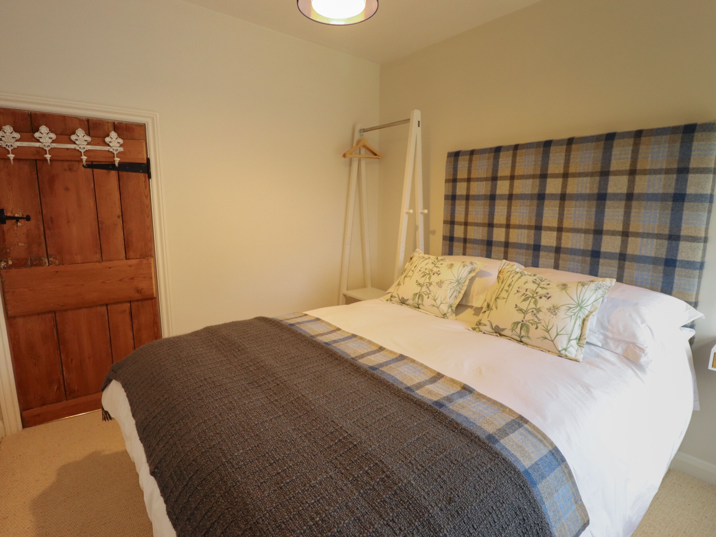 A bedroom with a bed, a wooden door, and a hanging coat rack.