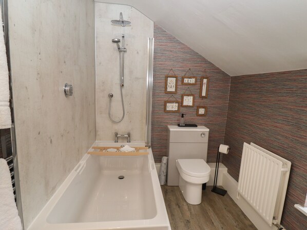 Un baño con bañera, ducha, inodoro y radiador.