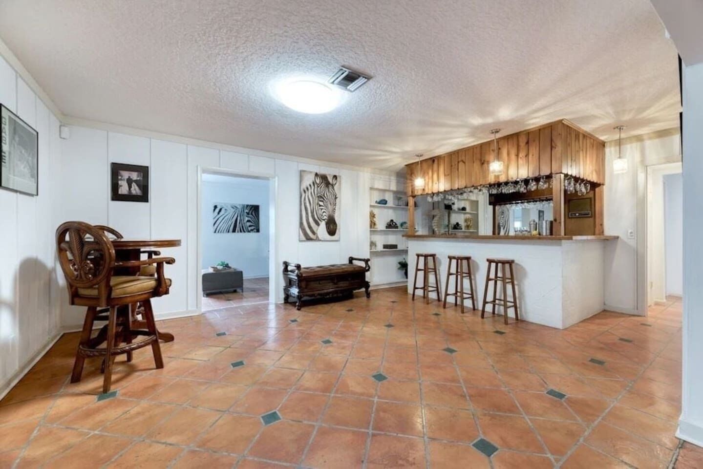 A spacious kitchen with a central island, a dining area with a wooden bench, and a bar area with stools.