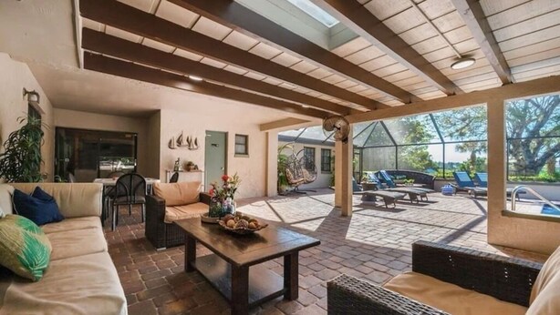 Amplia zona de patio con un área de estar techada, una mesa de comedor y vistas al exterior.
