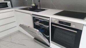 A modern kitchen with a built-in dishwasher, oven, and microwave. - Hypnos Residence (Ayios Dhometios)