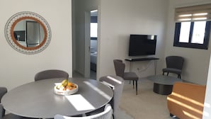 A modern living room with a round dining table, a flat-screen TV, and a comfortable seating arrangement. - Hypnos Residence (Ayios Dhometios)