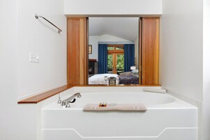 A bathroom with a large mirror, a bathtub, and a wooden vanity.