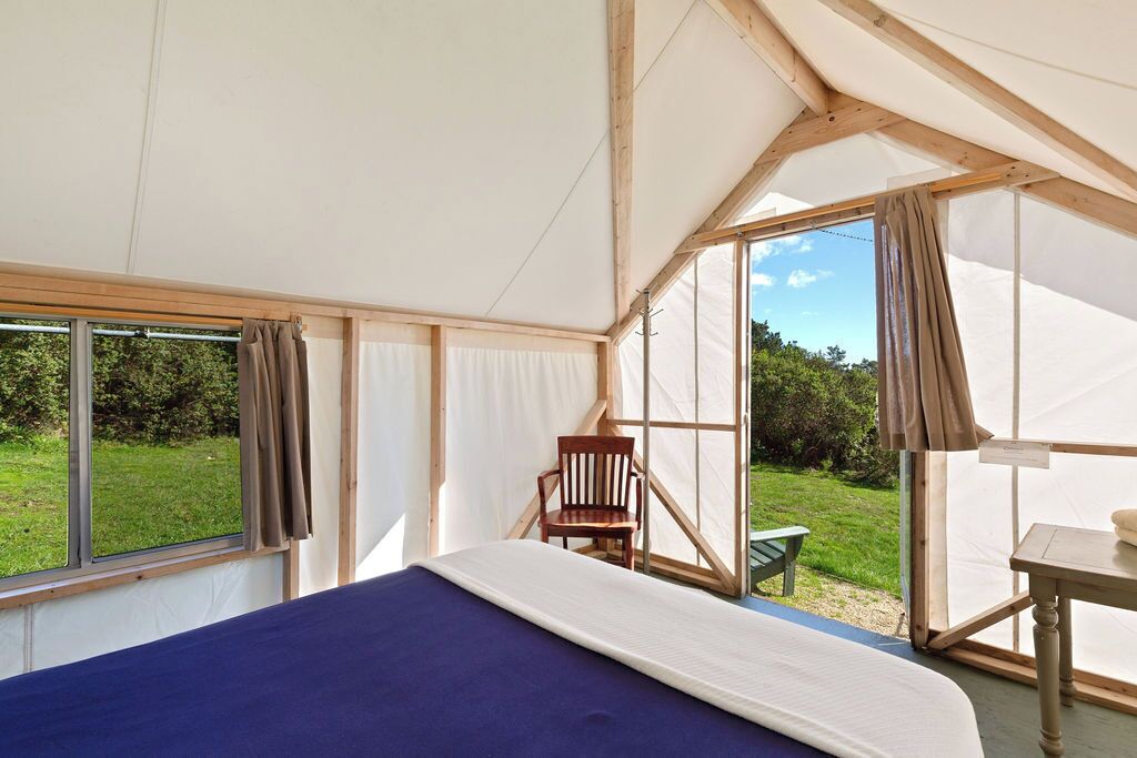 Una habitación con carpa, una cama, una silla y una mesa.