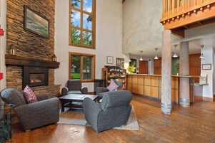 A spacious living room with a stone fireplace, comfortable seating, a coffee table, and a bar area with a view of the outdoors.
