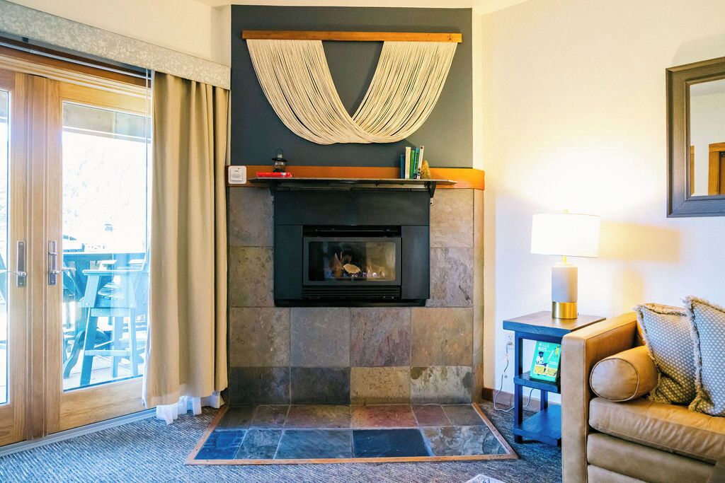 A living room with a fireplace, a sofa, a TV, and a lamp.