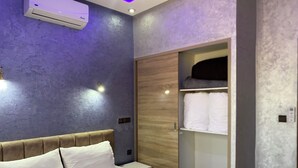 A modern hotel room with a bed, a wardrobe, and an air conditioning unit. - IGHIZ INN Resort (Errachidia)