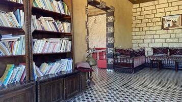A library with bookshelves, a red bench, a patterned floor, and a stone wall.