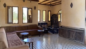 A room with a sofa, two small tables, a cabinet, and a patterned floor. - IGHIZ INN Resort (Errachidia)