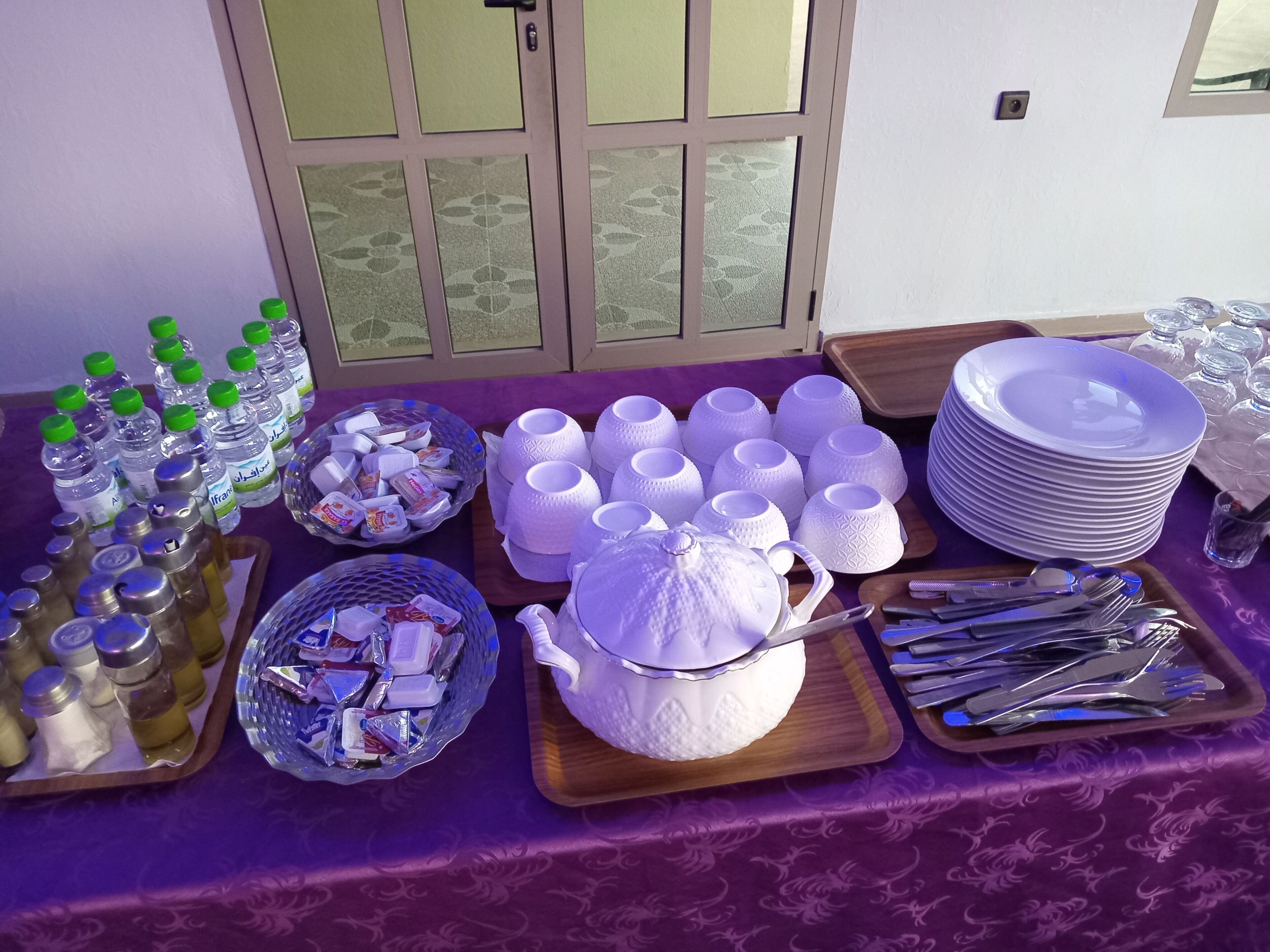 A table set with various food items, including bottles, bowls, plates, and cutlery.