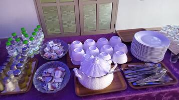 A table set with various food items, including bottles, bowls, plates, and cutlery.