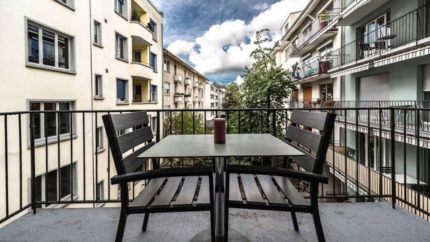 A balcony with a table and chairs, surrounded by apartment buildings. - Nice and big 1 BR flat city center/near lake (D8) (Zürich)