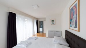 A modern hotel room with a large bed, a desk, and a painting on the wall. - Nice and big 1 BR flat city center/near lake (D8) (Zürich)