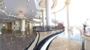Un hall d’entrée spacieux, doté de hauts plafonds, de colonnes richement décorées et d’un magnifique escalier.