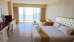Une chambre d’hôtel avec un lit, une télévision, un bureau et une vue sur l’océan.