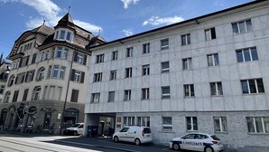 Ein mehrstöckiges Gebäude mit verschiedenen Baustilen, darunter ein Eckgebäude mit einem Turm und einer modernen Fassade.