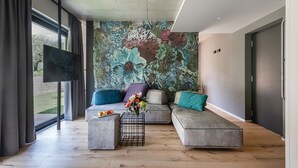 Un salon moderne avec un grand décor mural floral, des canapés gris et une table basse agrémentée de fleurs.