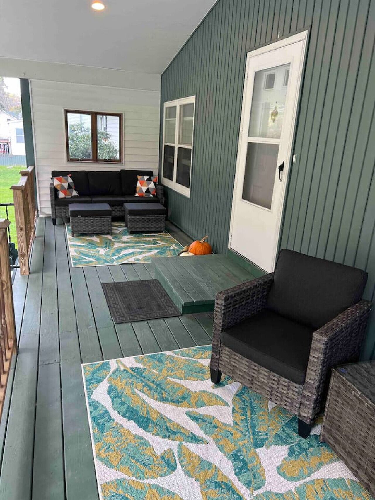 En inglasad veranda med en soffa, stolar och en matta.