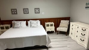 A bedroom with a large bed, a nightstand, a chair, and a dresser. - ​​2BR w/ Fireplace | Backyard Seating + Firepit (Wellsboro)