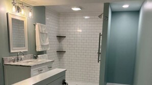 A modern bathroom with a shower, a sink, and a mirror. - ​​2BR w/ Fireplace | Backyard Seating + Firepit (Wellsboro)